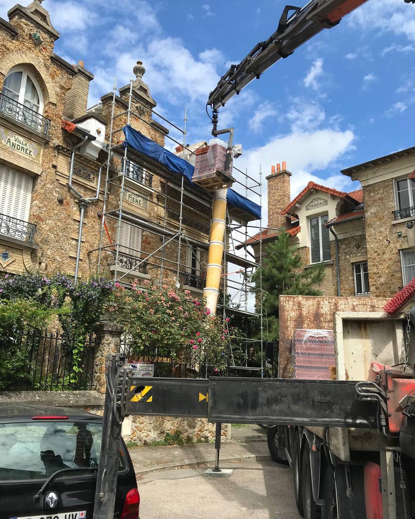 Camion-grue Maison Elite livrant des matériaux de couverture sur un échafaudage